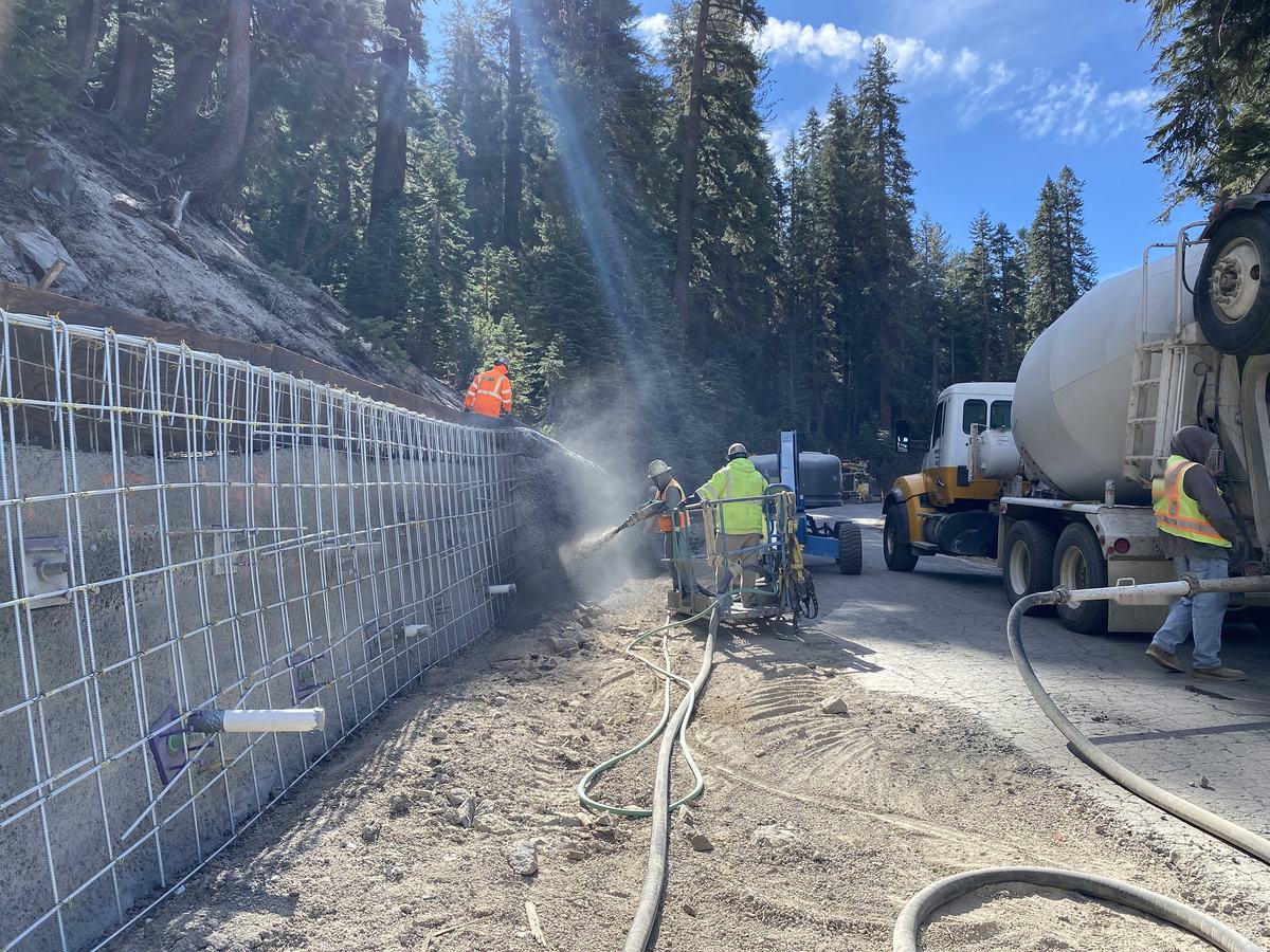 Workers spraying shotcrete onto a mesh-reinforced wall