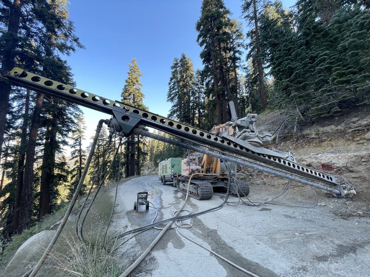 Drill mast installing soil nails into a slope